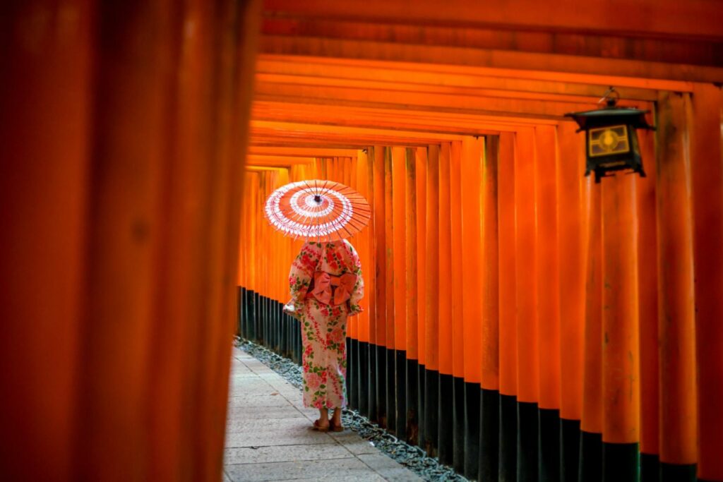 Kvinna med paraply går genom torii-portarna